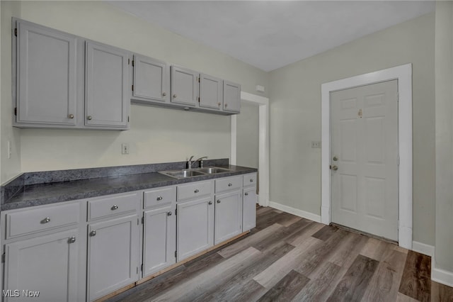 kitchen with dark countertops, baseboards, dark wood finished floors, and a sink