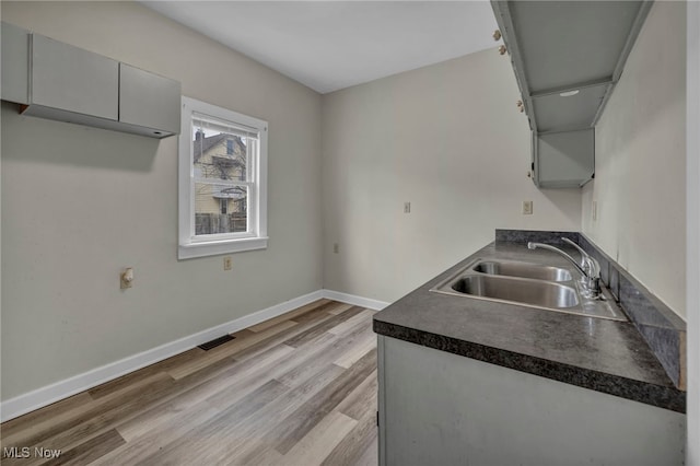 kitchen featuring dark countertops, gray cabinets, visible vents, a sink, and baseboards