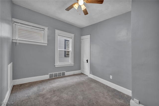 spare room with a ceiling fan, carpet, visible vents, and baseboards