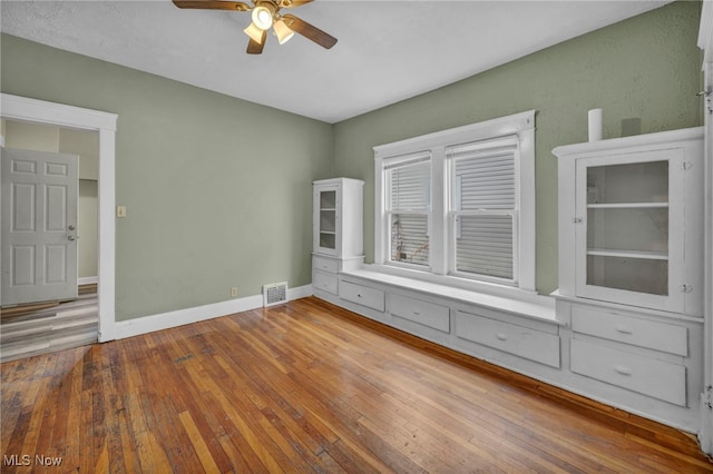 unfurnished bedroom featuring a ceiling fan, baseboards, visible vents, and hardwood / wood-style floors