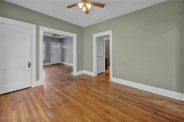 unfurnished room with wood-type flooring, baseboards, and a ceiling fan