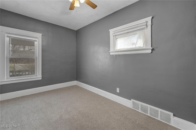 carpeted spare room with ceiling fan, visible vents, and baseboards