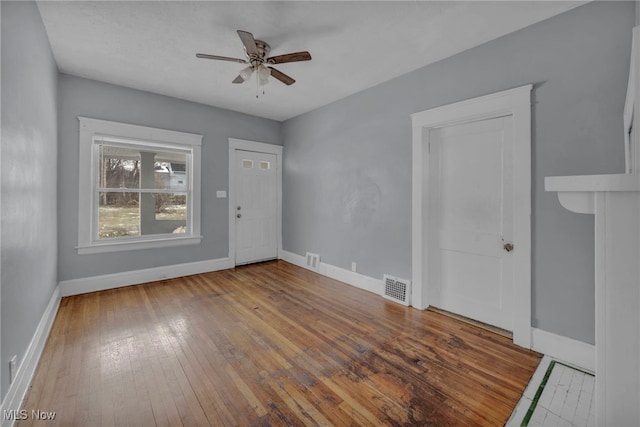 spare room with baseboards, visible vents, ceiling fan, and hardwood / wood-style floors