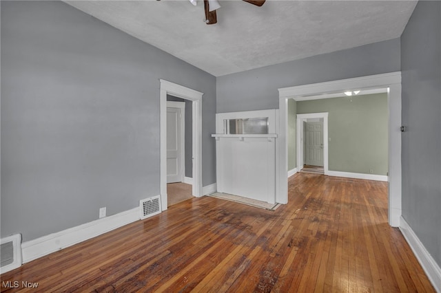 unfurnished room with baseboards, wood-type flooring, visible vents, and a ceiling fan