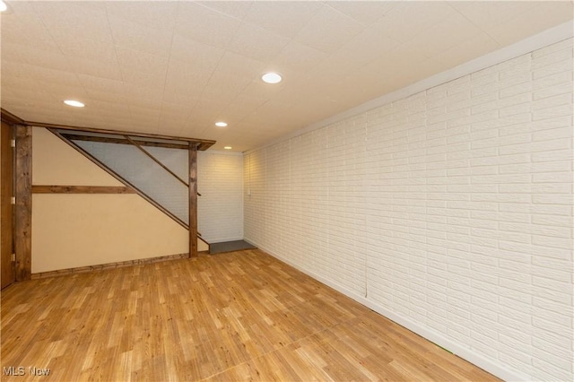 finished basement featuring brick wall, light wood-type flooring, and recessed lighting