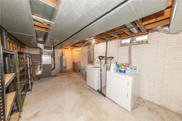 unfinished basement with brick wall, water heater, electric panel, heating unit, and washer and clothes dryer