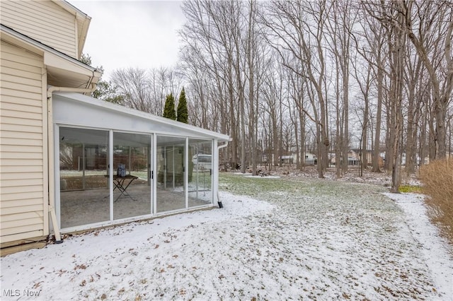 yard layered in snow with a sunroom