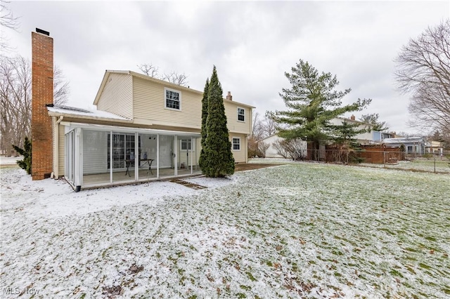 rear view of property with a chimney, fence, and a sunroom