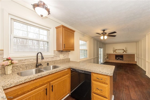 kitchen with a peninsula, dark wood-type flooring, a sink, dishwasher, and tasteful backsplash