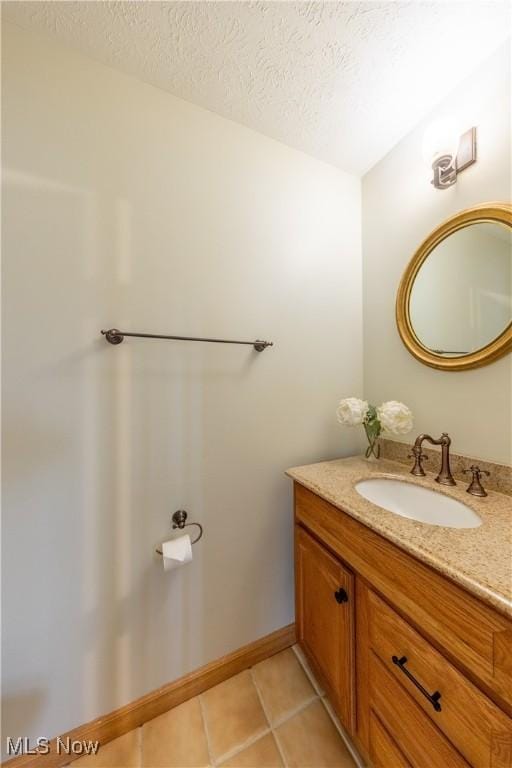 bathroom featuring vanity, baseboards, a textured ceiling, and tile patterned floors