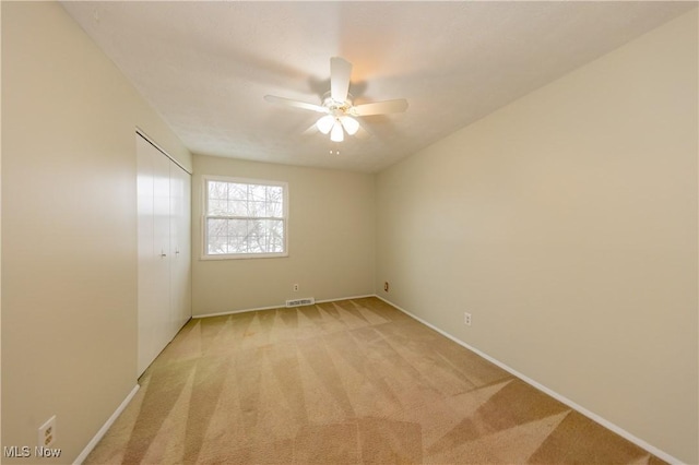 unfurnished room with light carpet, baseboards, visible vents, and a ceiling fan