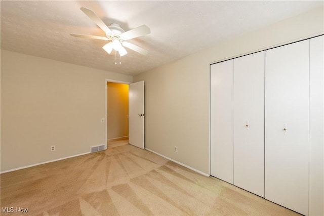 unfurnished bedroom with light carpet, baseboards, visible vents, ceiling fan, and a closet