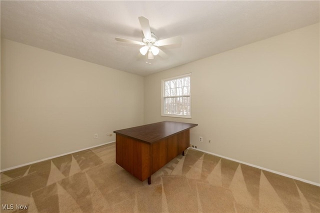 office featuring light carpet, baseboards, and a ceiling fan