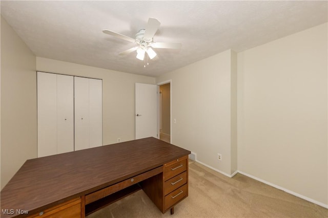 home office with light carpet, ceiling fan, and baseboards