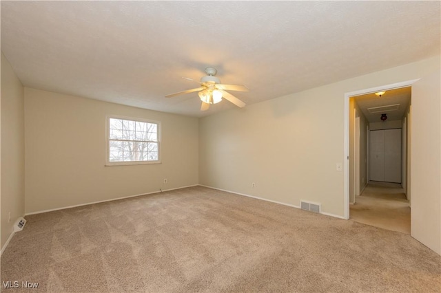 carpeted spare room with visible vents and a ceiling fan