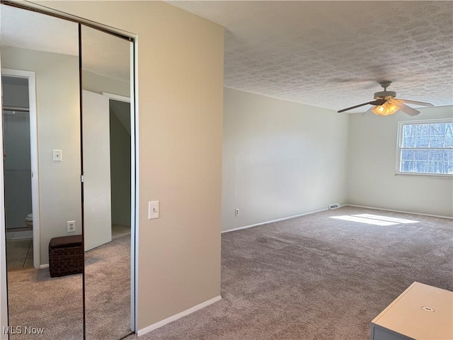 carpeted spare room with baseboards, a ceiling fan, and a textured ceiling