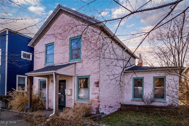 view of front of property with a chimney, fence, and brick siding