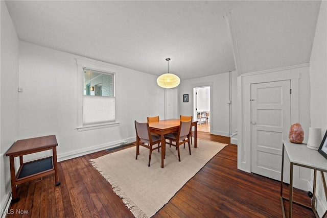 dining space featuring dark wood-type flooring and baseboards