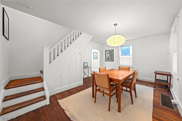 dining area with wood-type flooring, visible vents, baseboards, and stairs