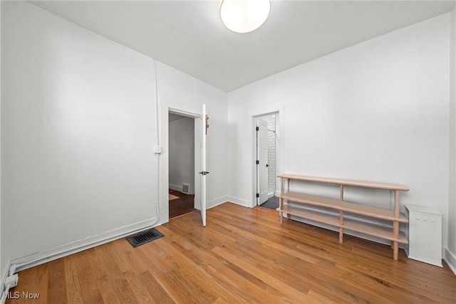 unfurnished room featuring light wood-style flooring, visible vents, and baseboards