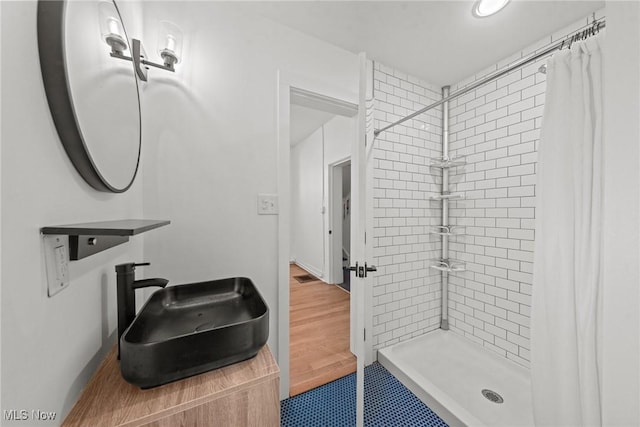 bathroom with a stall shower, visible vents, a sink, and wood finished floors