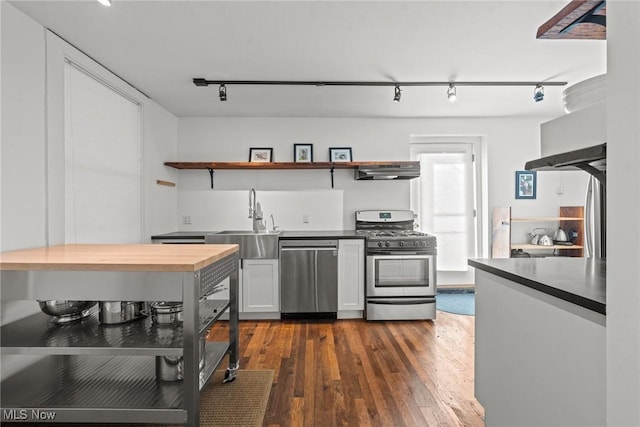 kitchen featuring butcher block counters, a sink, appliances with stainless steel finishes, open shelves, and dark wood finished floors