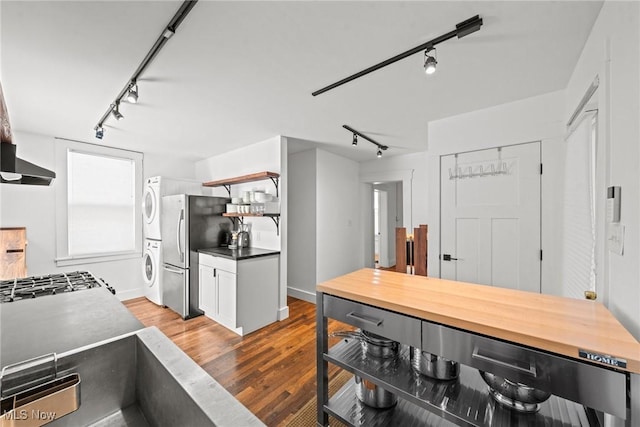 kitchen with stacked washer and dryer, wood finished floors, freestanding refrigerator, open shelves, and rail lighting