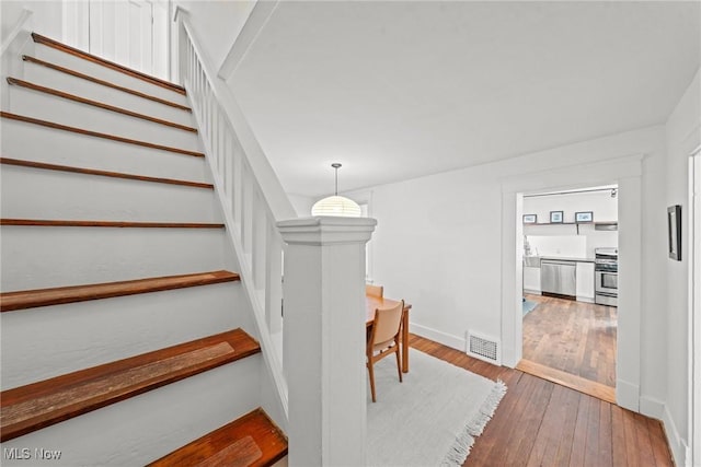 stairs with hardwood / wood-style floors, visible vents, and baseboards