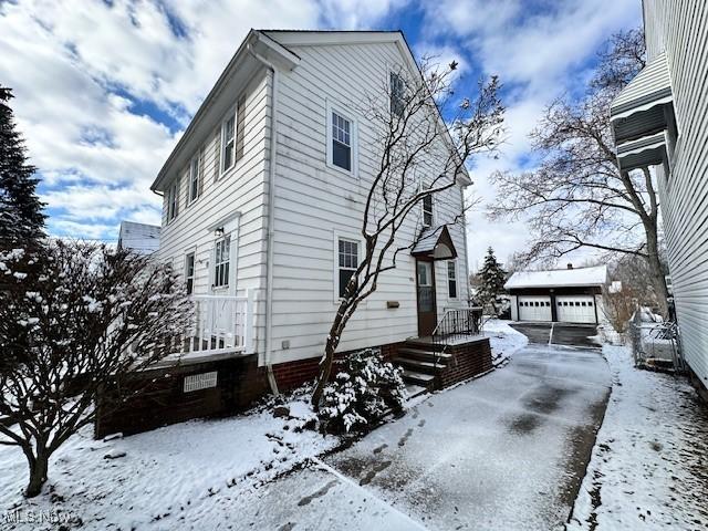 view of snowy exterior with a garage and an outdoor structure