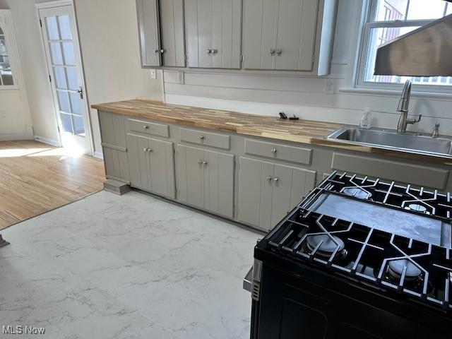 kitchen with black gas stove, gray cabinets, wooden counters, and a sink