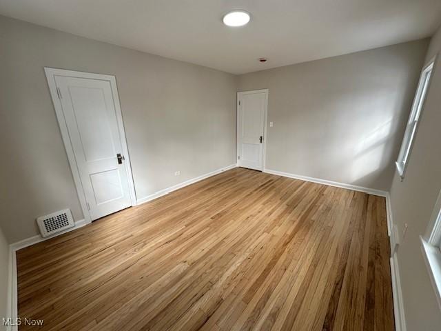 empty room with light wood-type flooring, baseboards, and visible vents