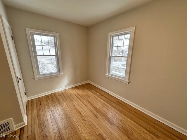 unfurnished room with baseboards, visible vents, and wood finished floors