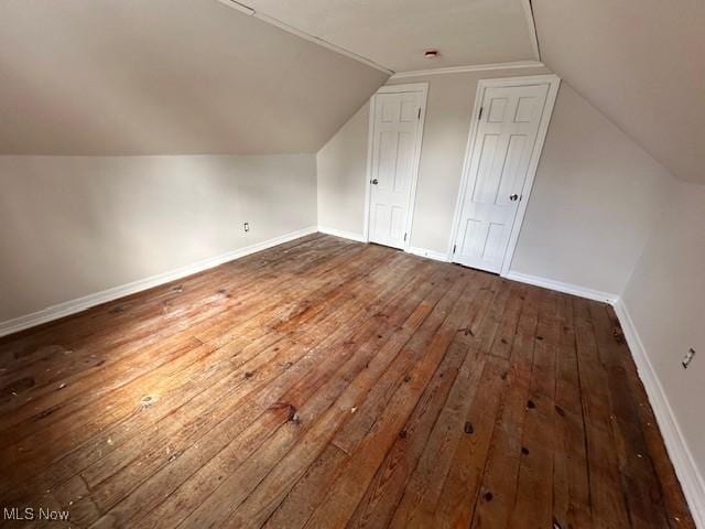 bonus room featuring baseboards, vaulted ceiling, and dark wood-style flooring