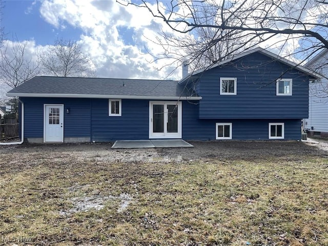 back of property with a shingled roof, a patio area, and a chimney