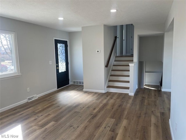 entrance foyer featuring stairs, dark wood finished floors, visible vents, and baseboards