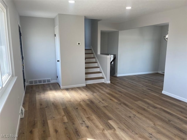 empty room with baseboards, visible vents, wood finished floors, stairs, and recessed lighting