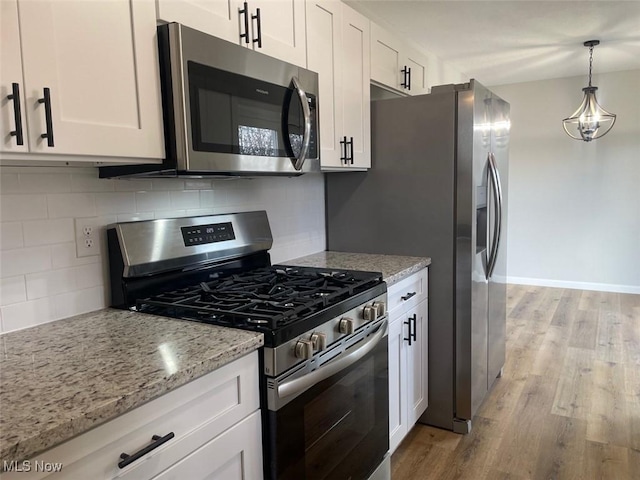 kitchen with stainless steel appliances, white cabinetry, and light wood finished floors