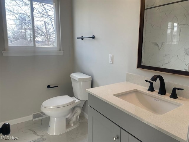 bathroom with toilet, visible vents, vanity, baseboards, and marble finish floor