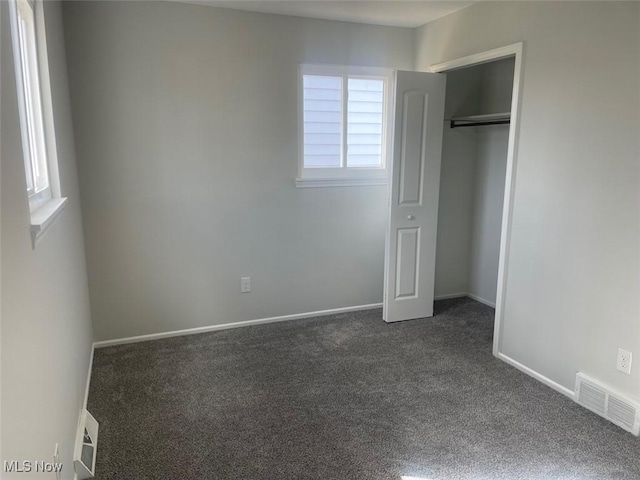 unfurnished bedroom with baseboards, visible vents, and dark colored carpet