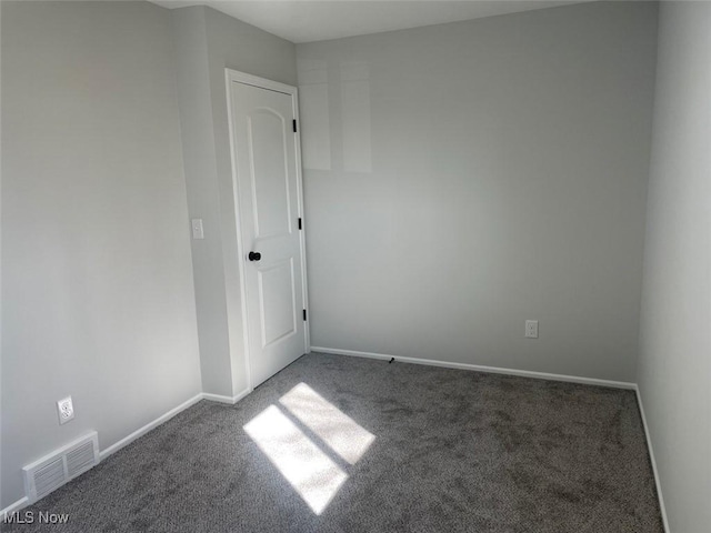 empty room with carpet floors, visible vents, and baseboards