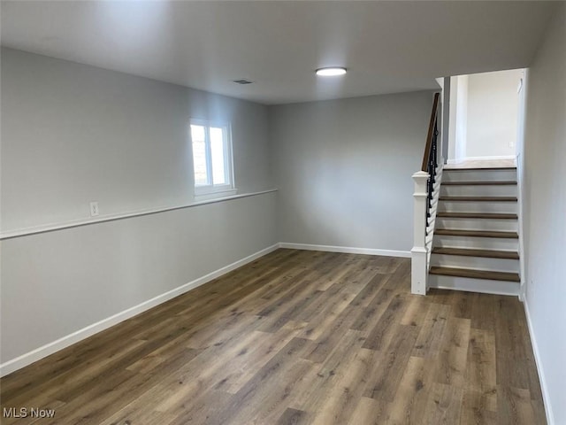 below grade area featuring visible vents, stairway, baseboards, and wood finished floors