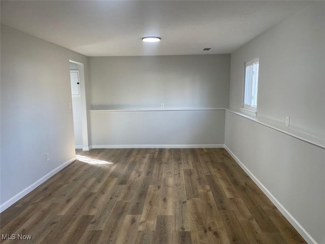 spare room with visible vents, baseboards, and wood finished floors