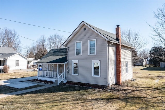 view of front of house featuring a porch, a front yard, a shingled roof, and a chimney