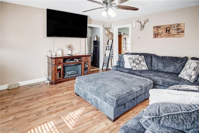 living area with light wood-style floors, visible vents, ceiling fan, and baseboards