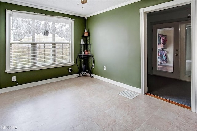 spare room with a ceiling fan, visible vents, crown molding, and baseboards