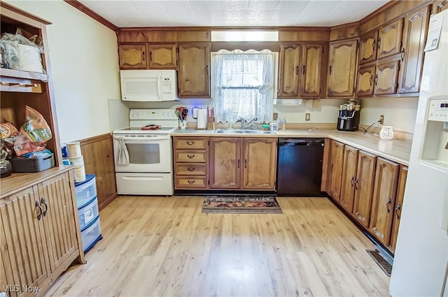 kitchen with light wood finished floors, light countertops, white appliances, and a sink