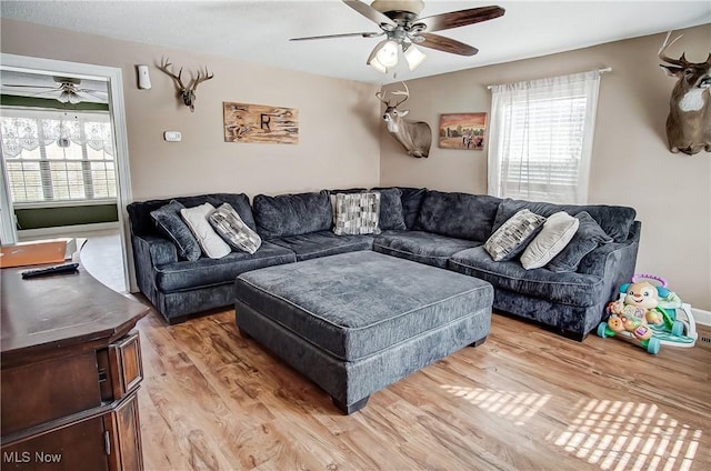 living area with a healthy amount of sunlight, light wood-style flooring, and ceiling fan