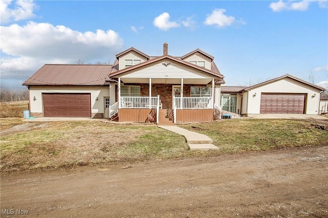 view of front of property featuring dirt driveway, a chimney, metal roof, an attached garage, and covered porch