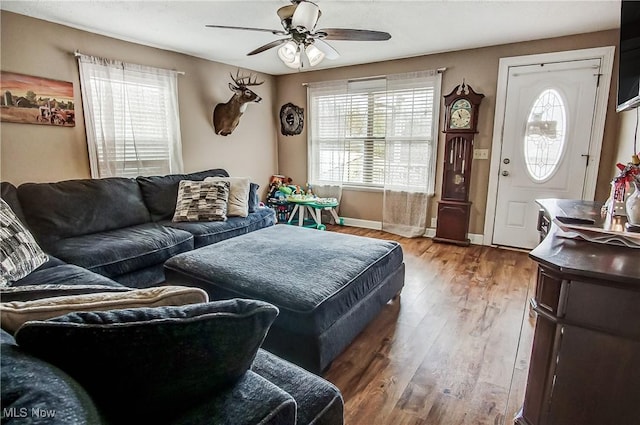 living area with ceiling fan, light wood-style flooring, a wealth of natural light, and baseboards