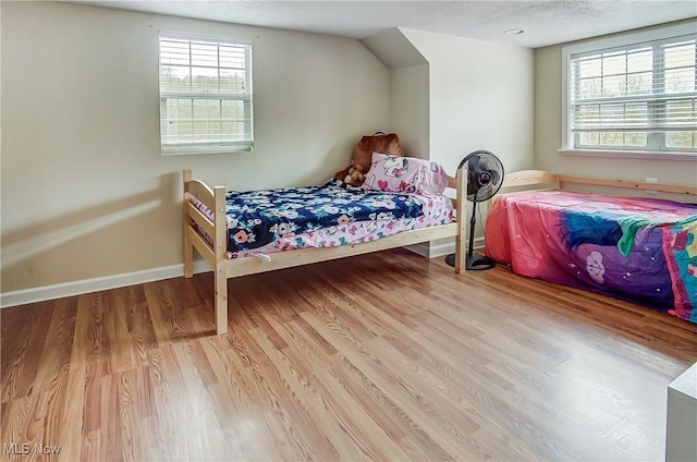 bedroom featuring a textured ceiling, baseboards, and wood finished floors